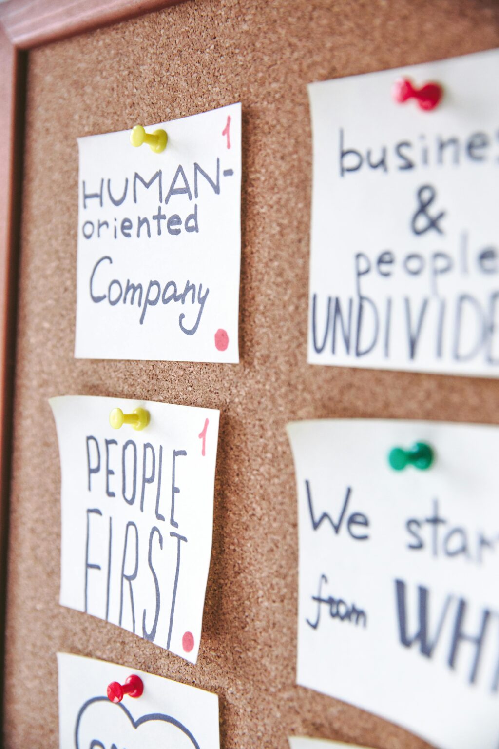 Pinned sticky notes on a cork board with motivational messages for business inspiration.